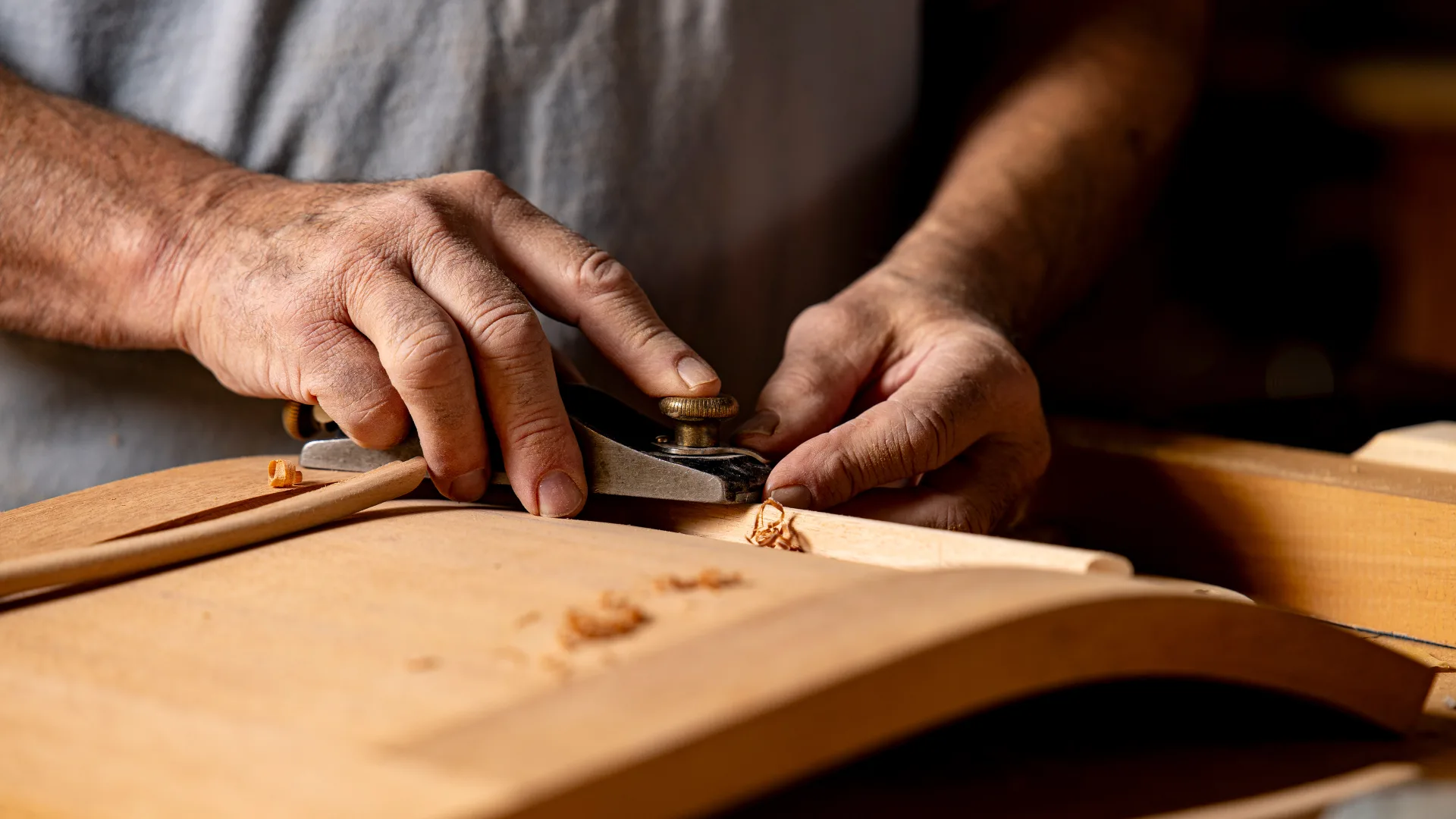 Craftsperson planing a wood panel on a bench in Oxford